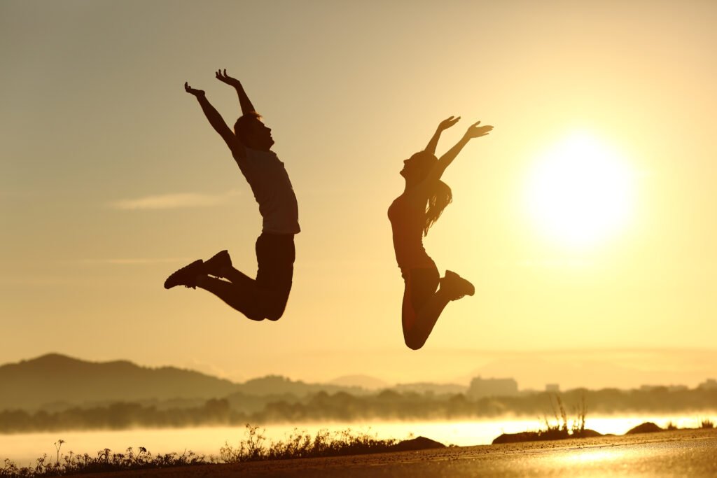Fitness,Couple,Jumping,Happy,At,Sunset,With,The,Sun,In